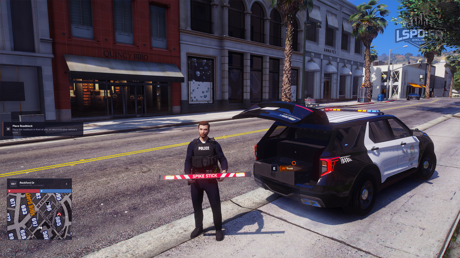 Officer carrying a folded spike strip beside a patrol vehicle